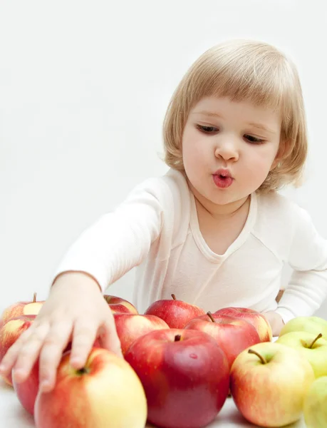 Das kleine Mädchen wählt einen roten Apfel aus — Stockfoto