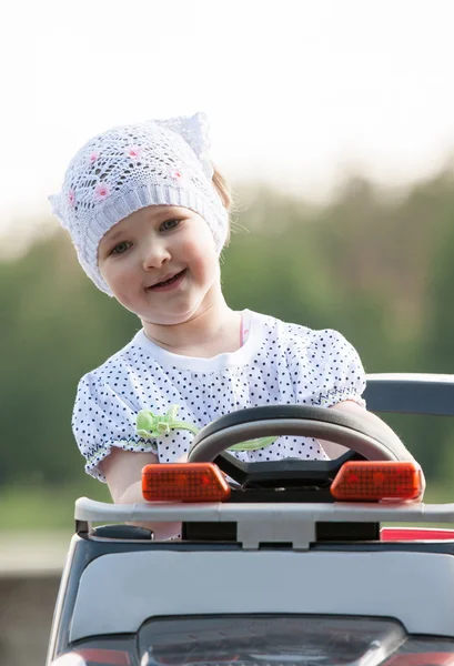 Lächelndes kleines Mädchen steuert Elektromobil — Stockfoto