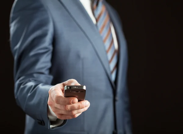 Empresario sosteniendo teléfono celular — Foto de Stock