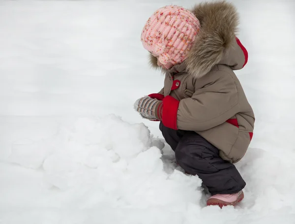 Liten flicka spelar med snöbollar — Stockfoto