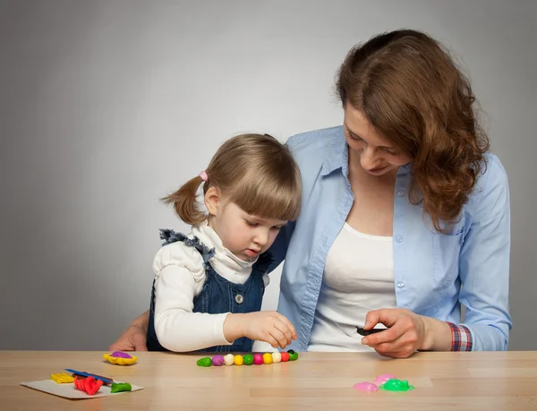 Молодая мать и ее дочь моделирование с пластилином — стоковое фото