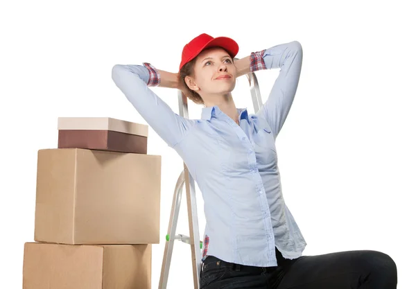 Smiling young woman near a pile of boxes — Stock Photo, Image