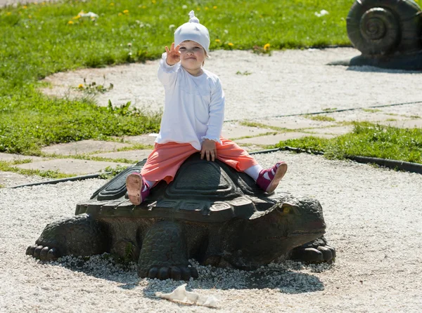 Baby sitting on a stone turtle — Stock Photo, Image