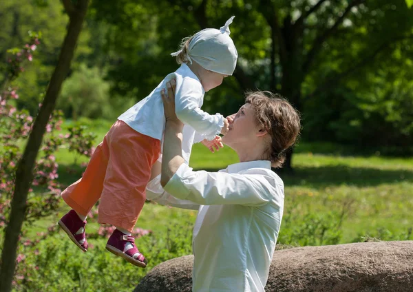 Счастливая мать, гуляющая со своей маленькой девочкой в летнем парке — стоковое фото