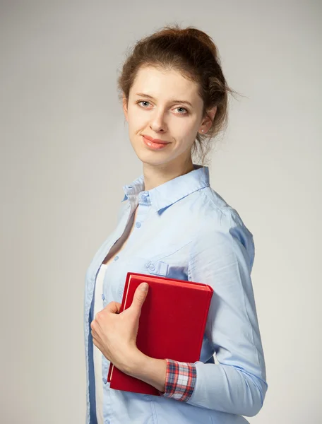 Chica sonriente sosteniendo un libro rojo — Foto de Stock
