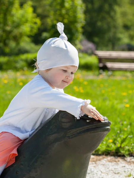 Baby flicka sitter på en sten groda — Stockfoto