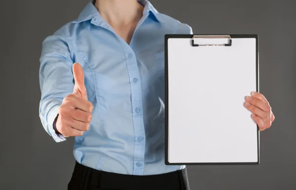 Businesswoman holding clipboard and showing thumb up — Stock Photo, Image