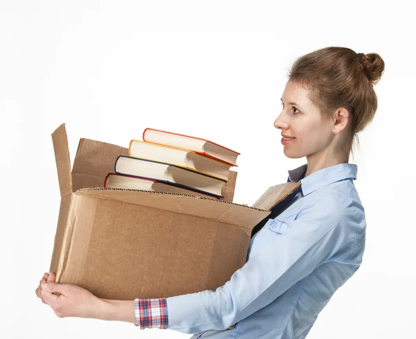 Mulher sorridente carregando uma caixa com livros — Fotografia de Stock