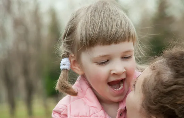 Счастливая молодая мать воспитывает свою улыбающуюся маленькую дочь — стоковое фото