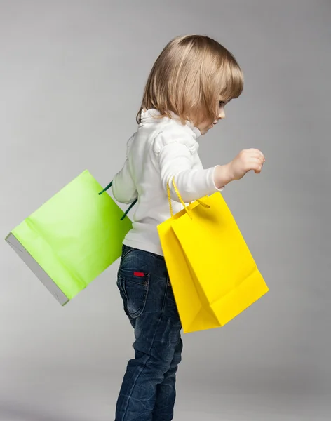Niña sosteniendo bolsas de compras multicolores —  Fotos de Stock