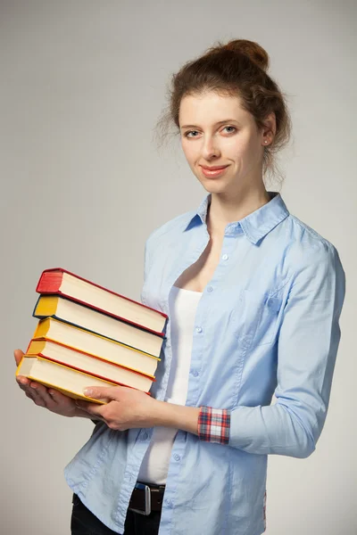 Usmívající se dívka drží hromádku knih — Stock fotografie