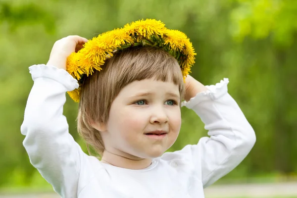 Petite fille essayant chapelet jaune fait de pissenlits — Photo