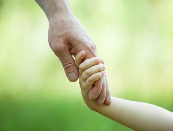 Hands of man and child holding together on light green background — Stock Photo, Image