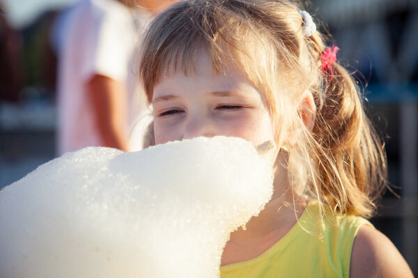 маленькая девочка ест сахарную вату
