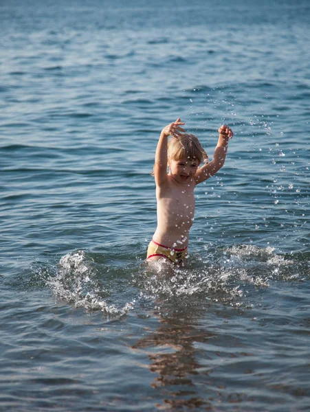 Маленькая девочка играет на берегу моря — стоковое фото