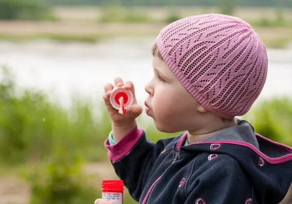 Söt liten flicka att göra såpbubblor i en park — Stockfoto