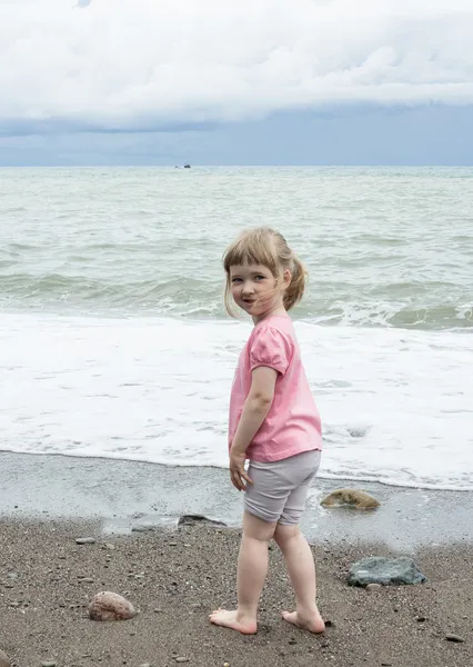 Leende liten flicka gå nära havsstranden — Stockfoto