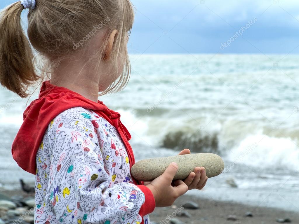 Little girl holding a big rock