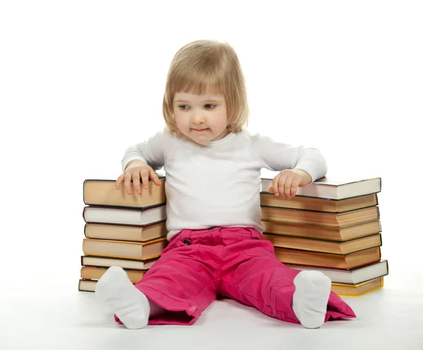 Маленькая девочка сидит среди книг — стоковое фото