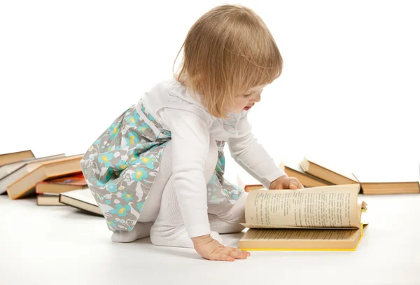 Malá dívka sedící mezi knihami — Stock fotografie