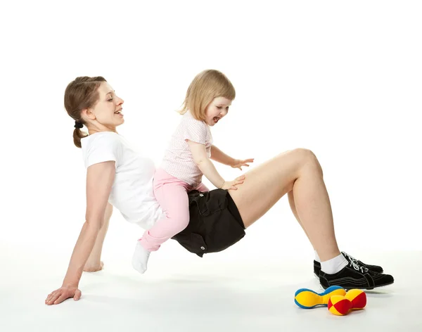 Joven madre haciendo ejercicios deportivos con su hija pequeña — Foto de Stock