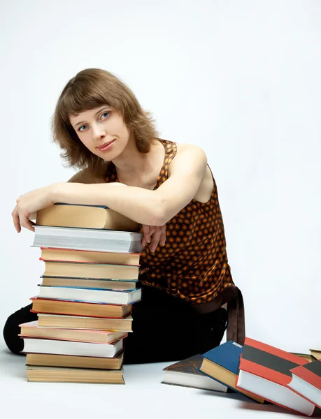 Mladá žena, sedící mezi knihami — Stock fotografie
