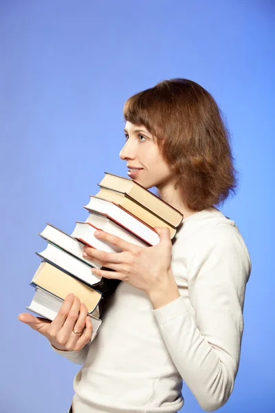 Улыбающаяся молодая женщина держит стопку книг — стоковое фото
