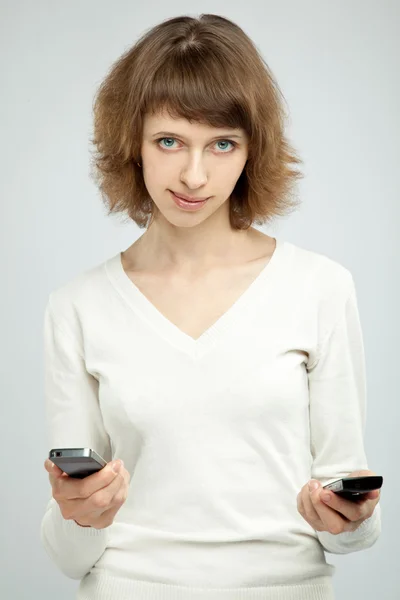 Mulher sorridente bonita segurando dois celulares — Fotografia de Stock