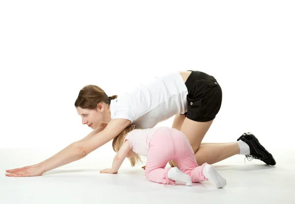 Молодая мама делает спортивные упражнения со своей маленькой дочерью — стоковое фото