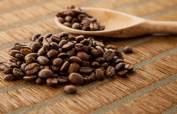 Manojo de granos de café y granos de café en una cuchara de madera sobre fondo de bambú — Foto de Stock