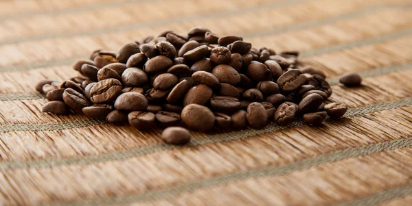 Unos granos de café sobre fondo de bambú — Foto de Stock