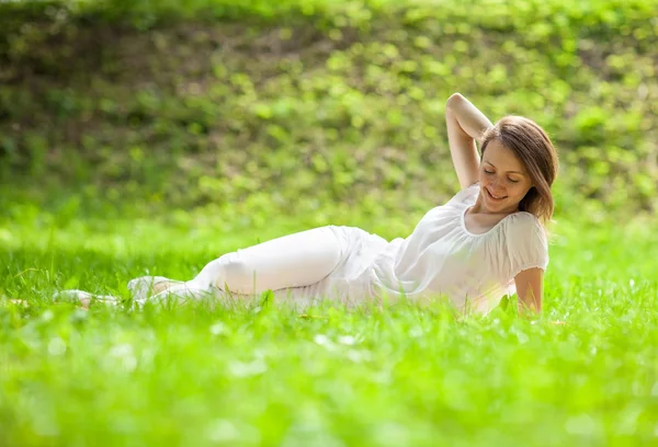 Attraktiv ung kvinna liggande på grönt gräs — Stockfoto