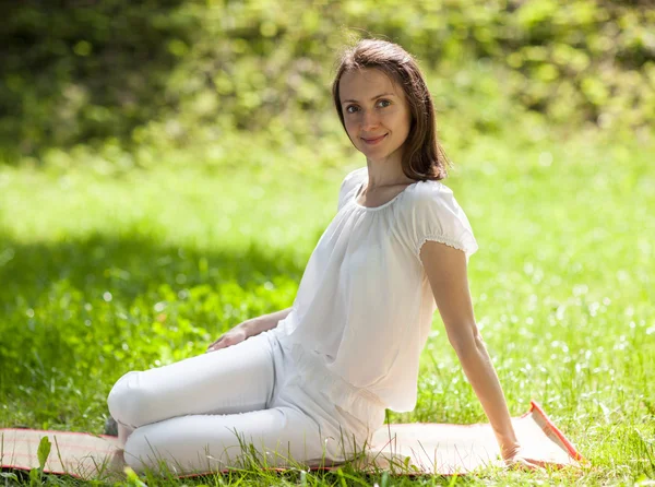 Aantrekkelijke jonge vrouw zittend op groen gras — Stockfoto