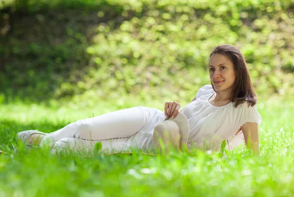 Aantrekkelijke jonge vrouw liggend op groen gras — Stockfoto