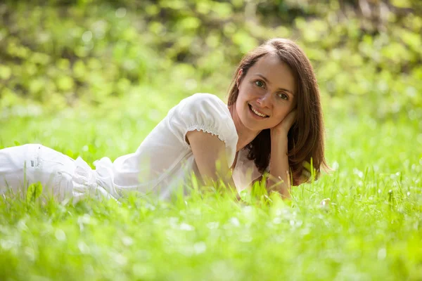 Mooi meisje liggend op een groen gras — Stockfoto