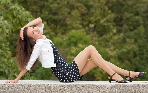 Usměvavá mladá žena sedí v letním parku — Stock fotografie
