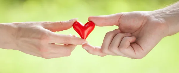 Eller kırmızı kalbi tutuyor.