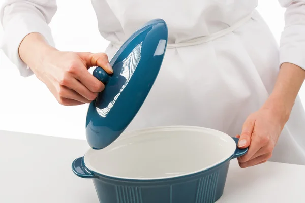 Vrouwelijke cook houden deksel boven blauw keramische pan — Stockfoto