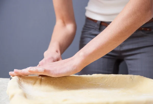 Hemmafru plattas en deg med en brödkavel — Stockfoto