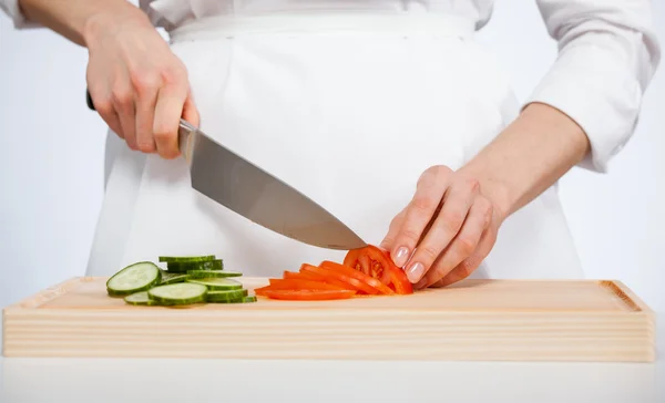 Cook cutting fresh cucumber and tomato — Stock Photo, Image