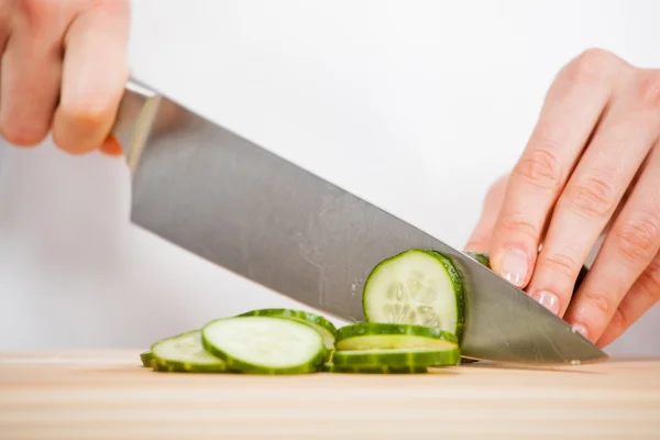 Female hands cutting fresh cucumber — Stock Photo, Image