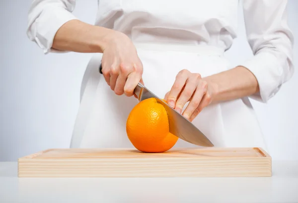 Kvinnans händer skära mogen orange — Stockfoto