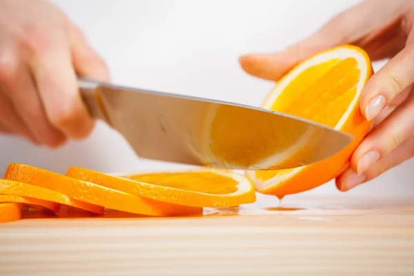 Frauenhände schneiden frische saftige Orange — Stockfoto