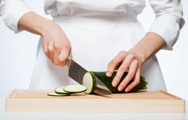 Vrouwelijke handen snijden courgette — Stockfoto