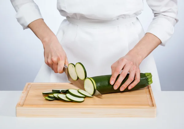 Mãos de cozinheiro cortando abobrinha — Fotografia de Stock