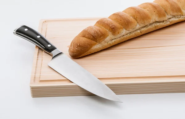 Pão e faca na tábua de cortar — Fotografia de Stock