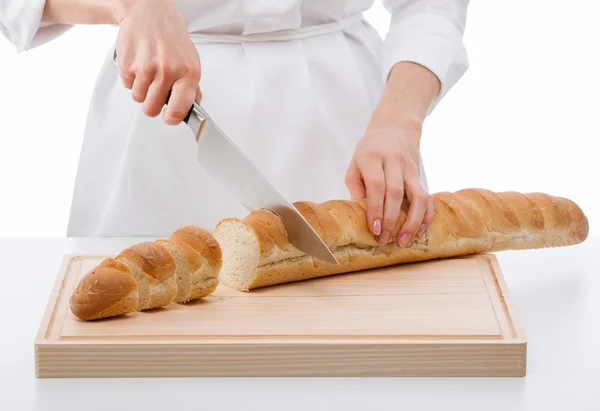 Cook cutting bread on wooden board — Stock Photo, Image