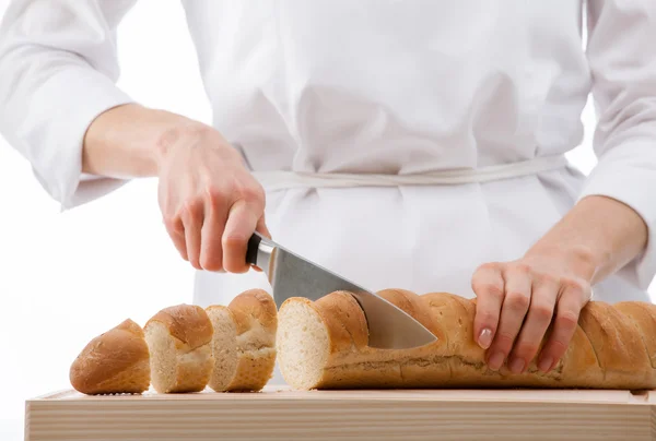 Cook cutting bread on wooden board — Stock Photo, Image