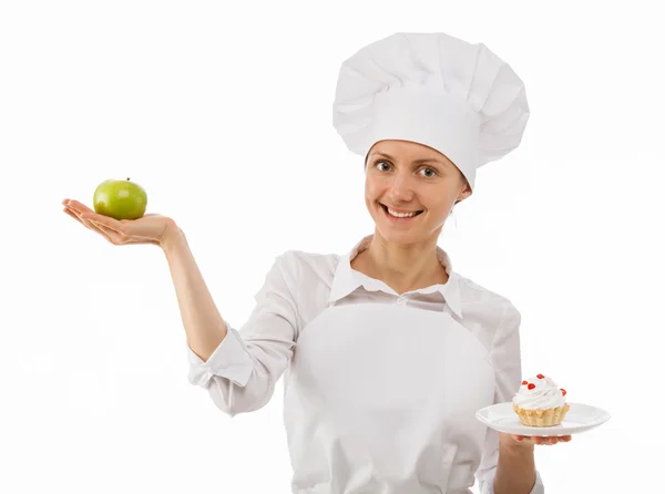 Mulher cozinheiro escolhe entre uma maçã e um bolo — Fotografia de Stock