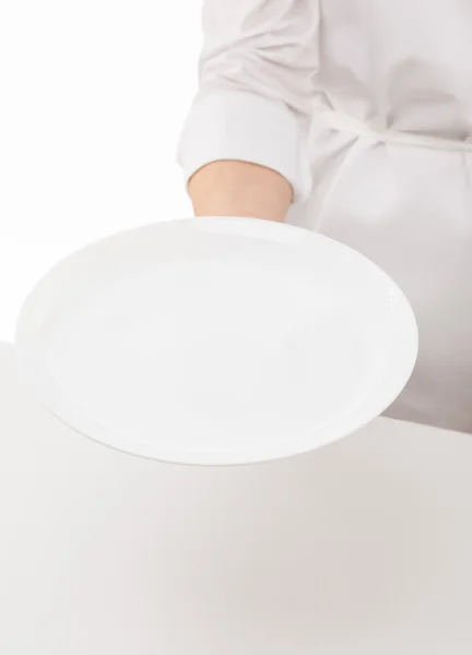 Рука Кука держит белую тарелку — стоковое фото